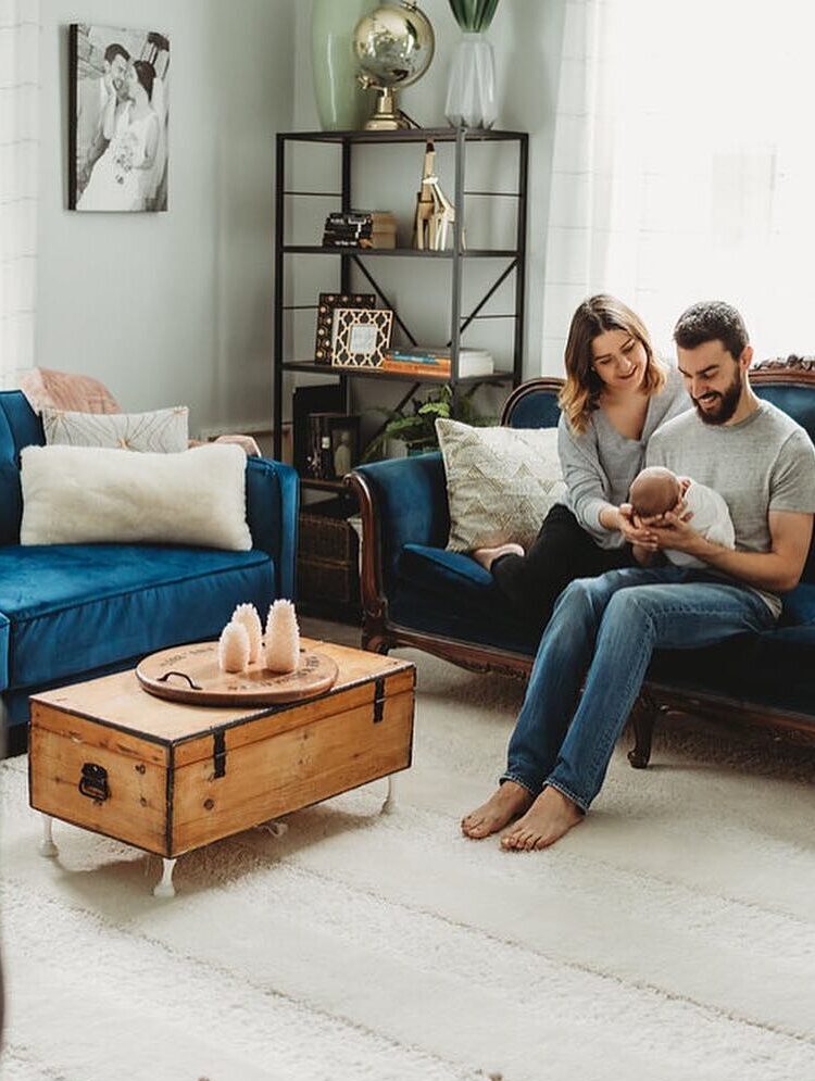 Young family sits on royal blue couch in bright and airy living room