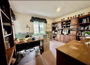 Dated green and cream office featuring 1980 wallpaper borders, mauve carpet, and "shoulder pad-esque" window valances.